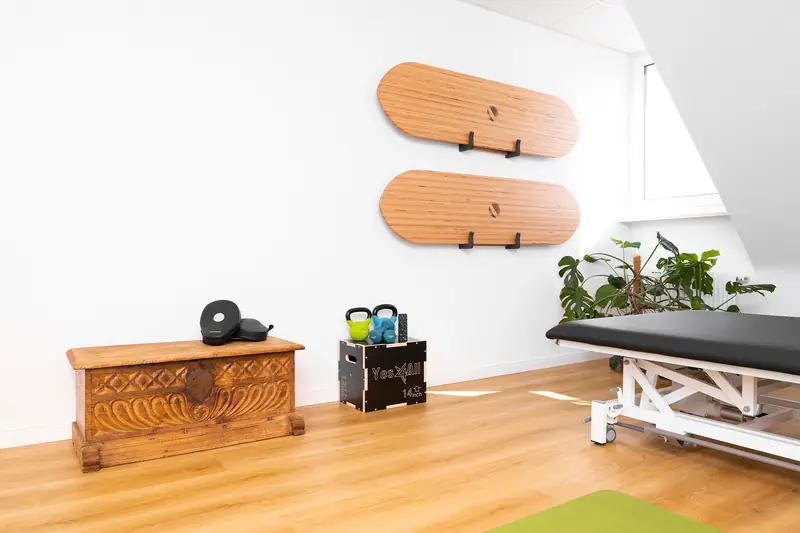 Treatment room with treatment table, wooden chest and balance boards on the wall